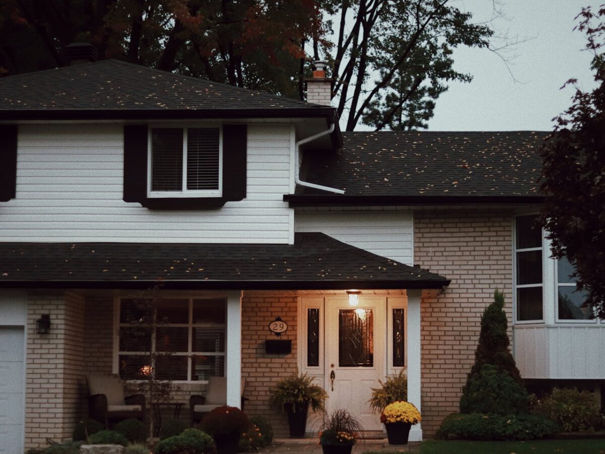 A cozy suburban house with a welcoming porch and lush potted plants at dusk.