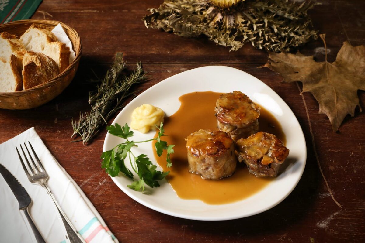 Delicious gourmet meat dish with sauce, parsley, and bread on a rustic table setting.