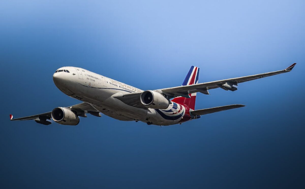 A close-up view of a commercial airplane flying against a clear blue sky.